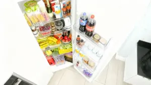 Interno di un frigorifero aperto con alimenti, bevande e frutta fresca disposti ordinatamente