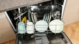 Interno di una lavastoviglie aperta con piatti e posate puliti