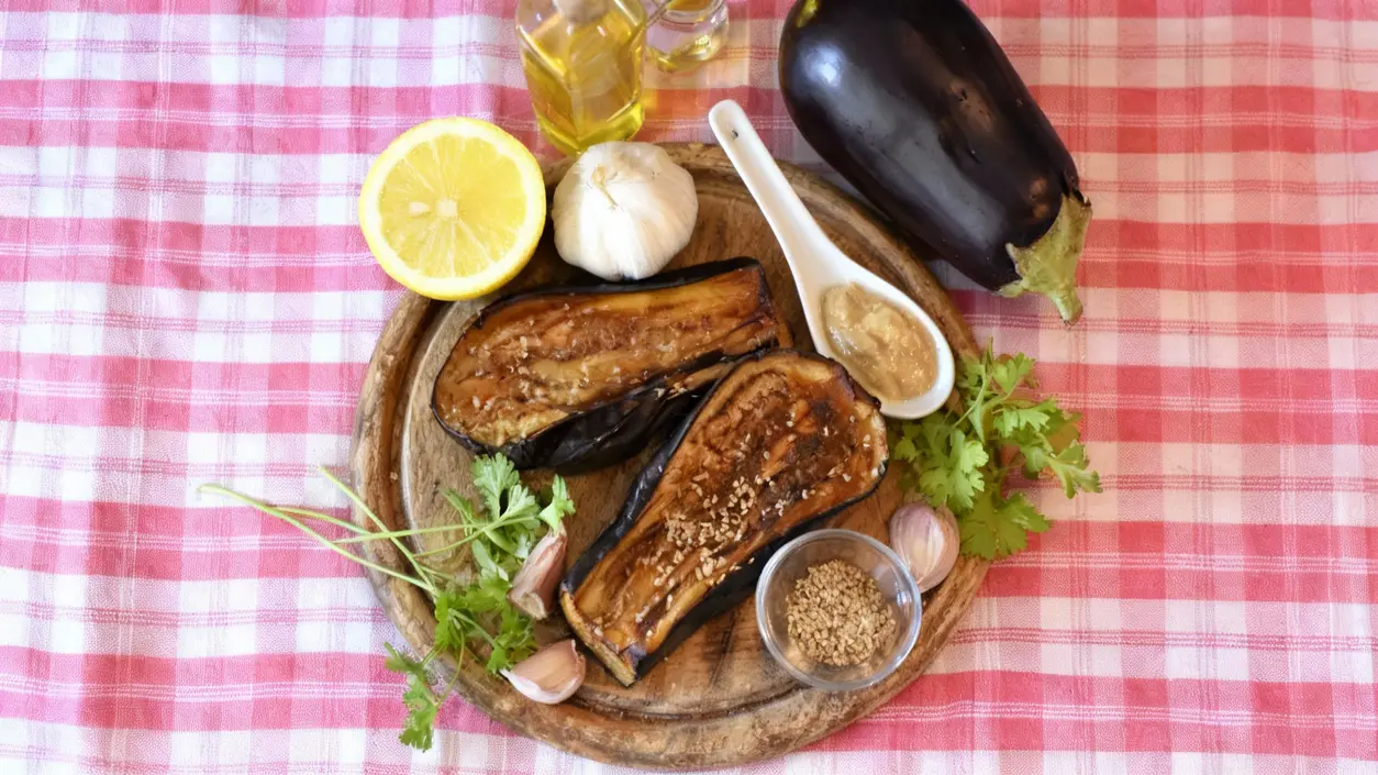 Melanzane grigliate su vassoio con ingredienti per marinatura su tovaglia rosa