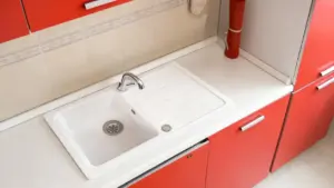 Lavello bianco su piano cucina con mobili rossi moderni