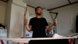 Una persona in lavanderia tiene delle grucce davanti a uno stendino con panni