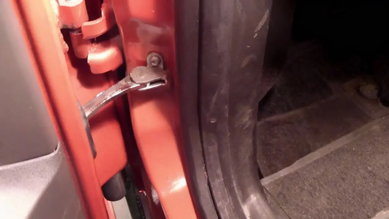 Cerniera di una porta d'auto vista da vicino, con segni di usura
