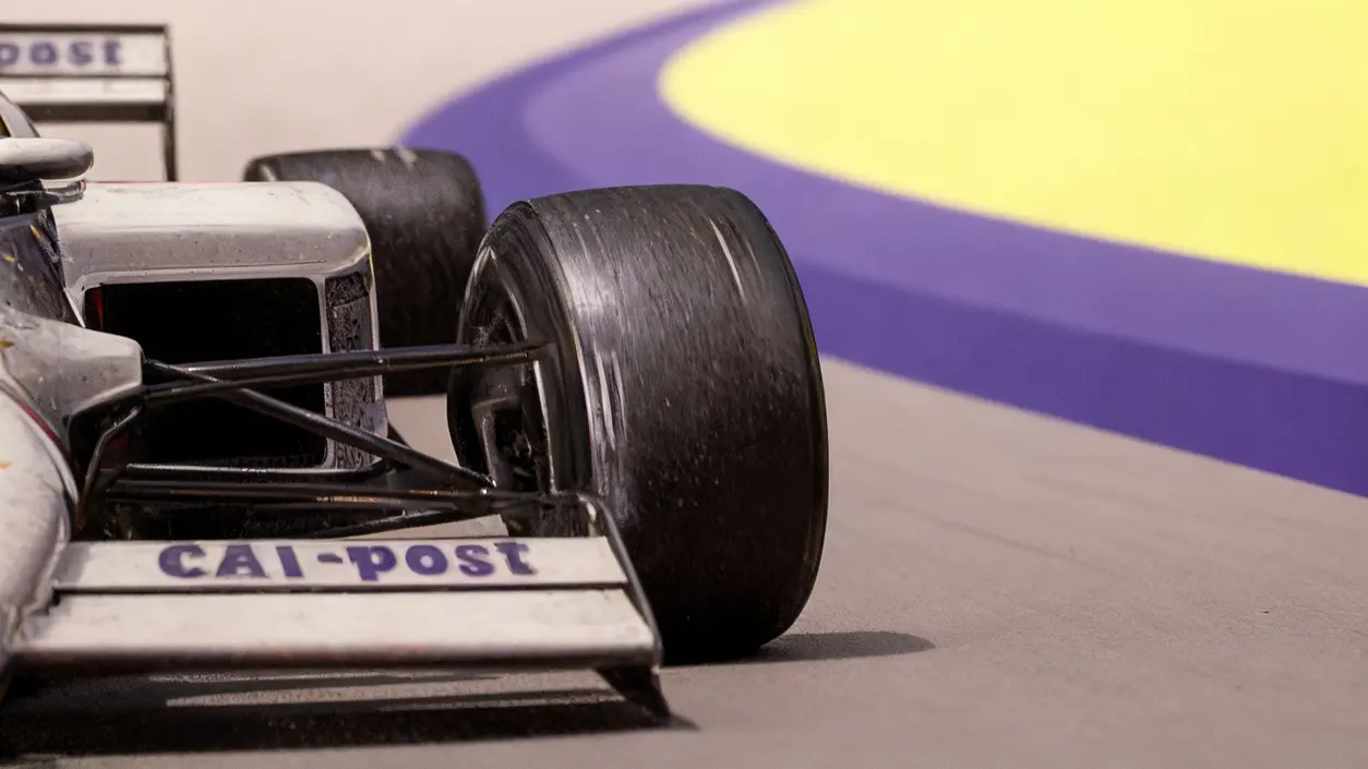 Dettaglio di un'auto da corsa con la scritta CAI-post su sfondo colorato