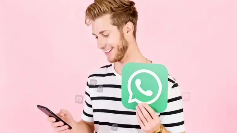 Una persona sorride guardando lo smartphone e tiene in mano il logo di WhatsApp