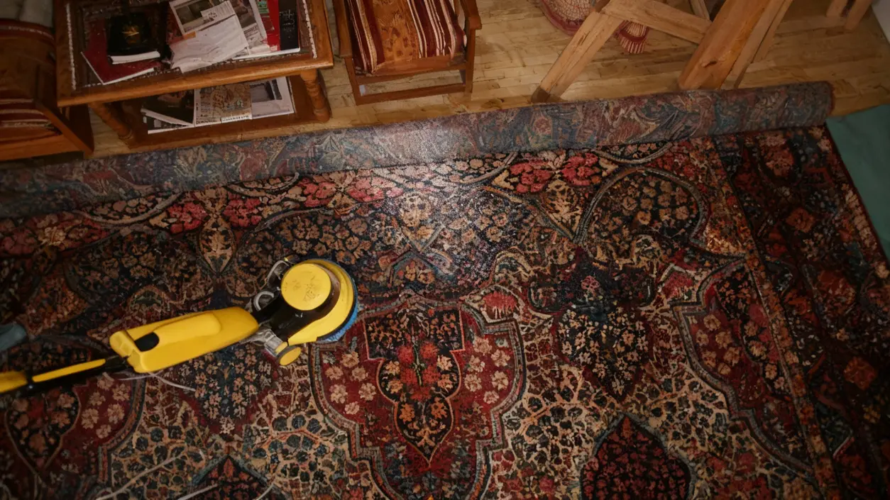 Pulizia di un tappeto persiano con una macchina a vapore su pavimento di legno