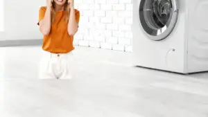 Una persona accanto a una lavatrice in una stanza luminosa, apparentemente frustrata