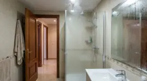 Bagno con doccia accesa e specchio appannato, porta aperta