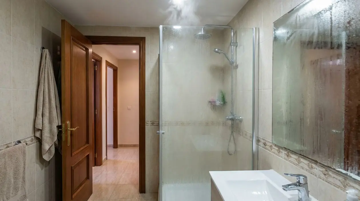 Bagno con doccia accesa e specchio appannato, porta aperta