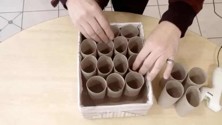 Mani che sistemano rotoli di carta igienica in una scatola per un'organizzazione domestica creativa