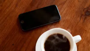 Uno smartphone e una tazza di caffè su un tavolo in legno